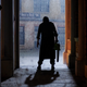 Leatherface stands in a doorway in silhouette, his chainsaw dangling from his hand.